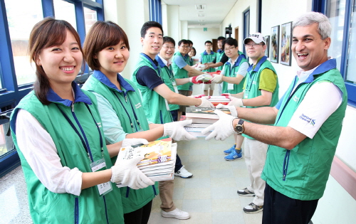  지난 14일 강원명진학교 착한도서관에서 도서관 건립 자원봉사 활동 일환으로 스탠다드차타드은행 아제이 칸왈 은행장(우측)과 임직원 자원봉사자들이 함께 책을 나르고 있다. ⓒ 스탠다드차타드은행