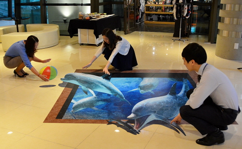  10일 오전 신도림 디큐브백화점 직원들이 2층 별관매장 통로 바닥에 설치된 트릭아트에서 실감나는 포즈를 취하고 있다. 디큐브백화점은 고객들에게 색다른 즐거움을 주고자 최근 2층 별관매장 통로 바닥에 돌고래, 연못, 하늘 등 더위를 날려주는 시원한 느낌의 트릭아트 3점을 설치했다. ⓒ 디큐브백화점