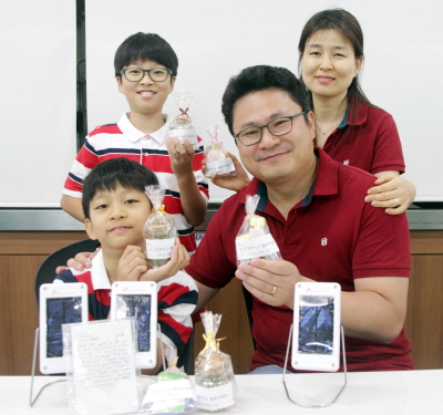  한 SK건설 임직원 가족이 봉사활동을 마친 뒤 직접 만든 태양광랜턴과 천연비누&middot;바스솔트를 들고 기념촬영을 하고 있다. ⓒ SK건설