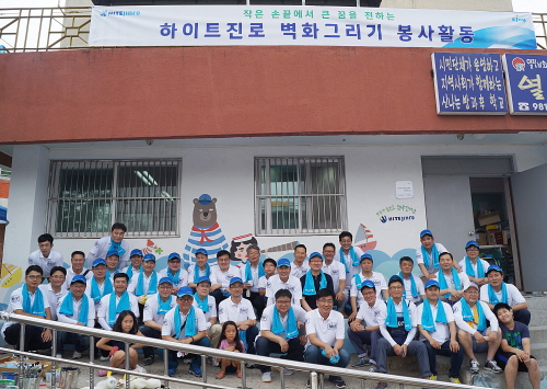  하이트진로 임직원들과 북부열린학교 초등학생들이 벽화그리기 봉사활동을 마친 후, 완성된 벽면을 배경으로 기념촬영을 하고 있다. ⓒ 하이트진로