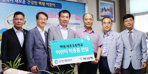  백령초등학교에서 하나은행 이형권 본부장(사진 좌측 두번째)과 인천광역시 김경선 시의원(사진 좌측 세번째) 등이 백령초등학교 민선재 교감(사진 좌측 네번째)와 북포 초등학교 조성철 교감(사진 좌측 여섯번째)에게 어린이 학용품을 전달하고 있다. ⓒ 하나은행
